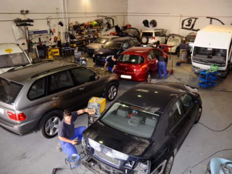 Varios coches en reparación dentro de nave grande