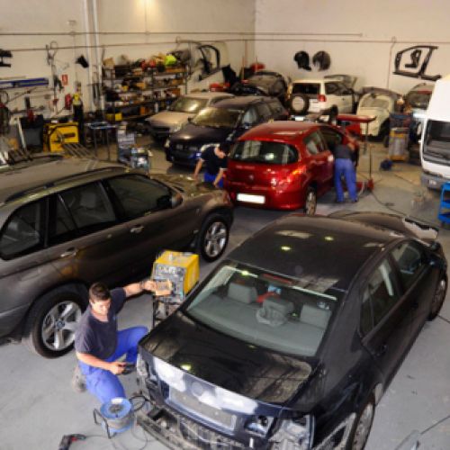 Varios coches en reparación dentro de nave grande