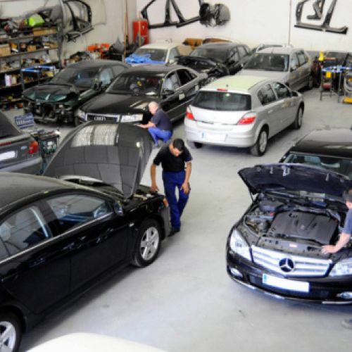 Varios coches y mecánicos en interior de nave grande