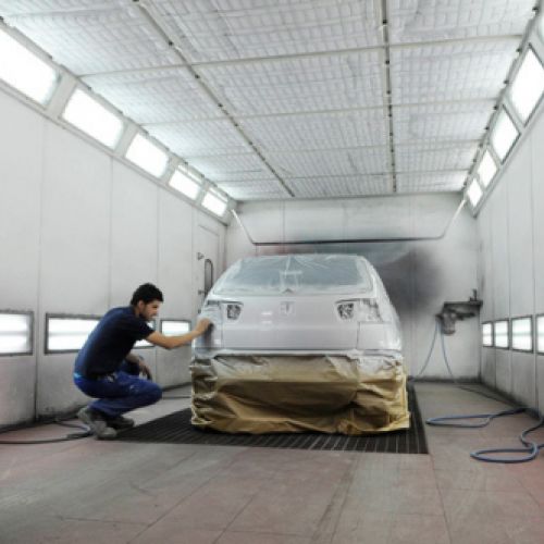 Mecánico en interior de cabina de pintura